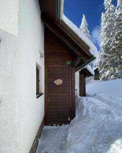 a building with a wooden door in the snow at Apartma Idila in Zreče