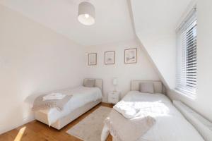 2 camas en una habitación blanca con ventana en Spacious One Bed loft Apartment, en Birchanger