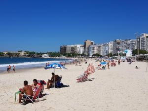 a group of people sitting in lawn chairs on a beach at Copacabana Front beach 2 in Rio de Janeiro