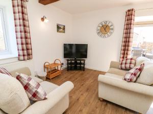 a living room with two chairs and a flat screen tv at Stable Cottage in Newport