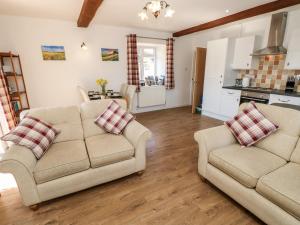 a living room with two couches and a kitchen at Stable Cottage in Newport