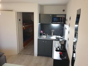 a small kitchen with a sink and a refrigerator at Studio cabine au Grau du roi à 3min à pied de la plage in Le Grau-du-Roi