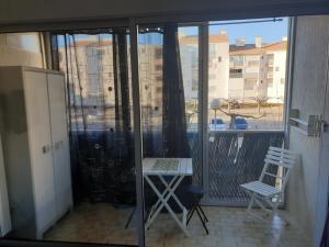 a balcony with a table and two chairs and a window at Studio cabine au Grau du roi à 3min à pied de la plage in Le Grau-du-Roi