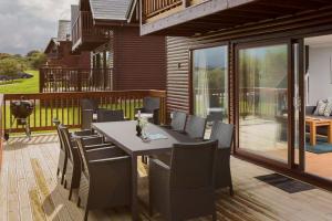 un patio con mesa y sillas en una terraza en Puffin Hot tub Lodge, 4 bedrooms Resort, Pool,Gym,Bar en Padstow