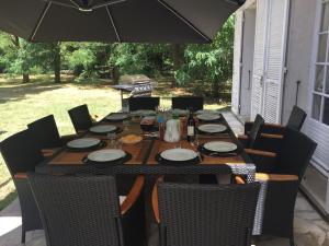 a wooden table with chairs and an umbrella at La Petite Trolière in Orval