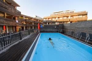 a person swimming in a swimming pool in a building at Hotel Planai by Alpeffect Hotels in Schladming