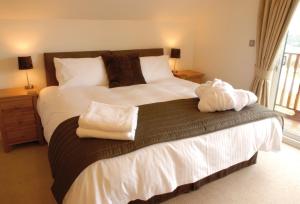 a bedroom with a large bed with towels on it at Puffin Hot tub Lodge, 4 bedrooms Resort, Pool,Gym,Bar in Padstow +37 photos