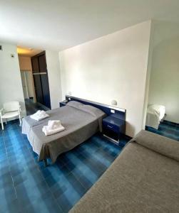 a bedroom with two beds and a blue tile floor at Hotel San Paolo in Palinuro