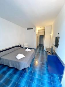 a room with a bed and a tv and blue floors at Hotel San Paolo in Palinuro