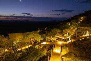 einen nächtlichen Blick auf einen hölzernen Gehweg mit Lichtern in der Unterkunft TimBila Safari Lodge in Omaruru