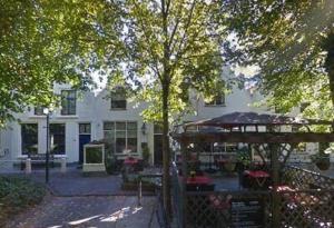 een groot wit gebouw met een tafel ervoor bij Voorstraat 30 Appartement in Colijnsplaat