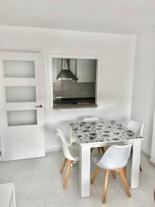 een witte eetkamer met een tafel en stoelen bij Apartamento Riviera con vistas al mar REF 024 in Benicàssim