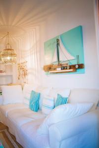 a white couch with pillows and a picture of a boat on the wall at Casa Eneida frente al mar in Tías