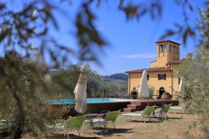 斯坎迪奇的住宿－Agriturismo Villa Guarnaschelli，一座带椅子和遮阳伞的大楼前的游泳池