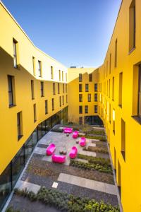 a row of pink chairs in a courtyard between two buildings at Prize by Radisson, Bonn City in Bonn
