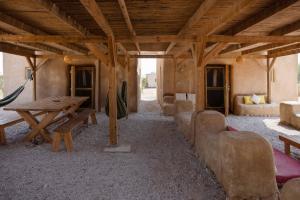 a living room with a wooden table and a couch at Desert Days mud cabin's Resort in Zuqim