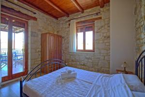 Villa Nipos by PosarelliVillas في Vryses: غرفة نوم بسرير في جدار حجري