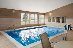 a large swimming pool in a room with a table and chairs at Super 8 by Wyndham Joliet I-55 N/Chicago in Joliet