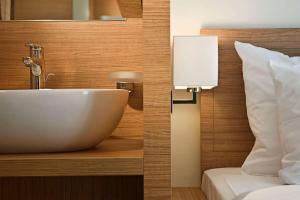 a bathroom with a sink next to a bed at Wyndham Köln in Cologne
