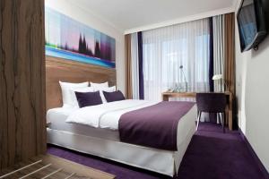 a bedroom with a bed and a desk and a television at Wyndham Köln in Cologne