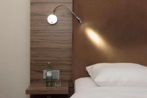 a bed with a lamp and a bottle on a night stand at Wyndham Köln in Cologne
