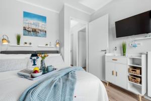 1 dormitorio blanco con 1 cama y TV de pantalla plana en Ostsee - Appartement Nr 162 "Strandzeit" im Strand Resort, en Heiligenhafen