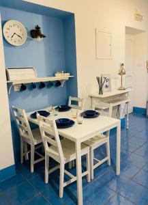 a white table with chairs and a clock on the wall at Sun&SeaGuestHouse Lido di Roma in Lido di Ostia