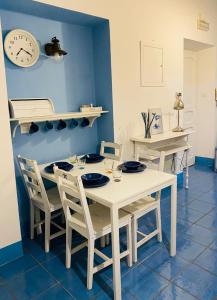 een witte tafel met stoelen en een klok aan de muur bij Sun&SeaGuestHouse Lido di Roma in Lido di Ostia