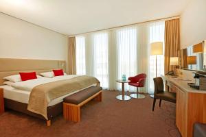
a hotel room with two beds and a desk at H4 Hotel München Messe in Munich
