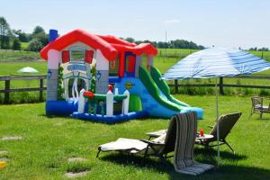 a childs play set in a field with an umbrella and chairs at Gospodarstwo Agroturystyczne Dworek Andrzejówka in Gardzień
