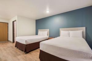 two beds in a room with blue walls at WoodSpring Suites Houston La Porte in La Porte