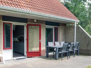 una mesa y sillas en un patio con puerta roja en Cosy holiday home with terrace near natural park in Lemele, en Lemele