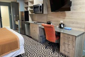 a room with a kitchen with a bed and a desk at Ramada by Wyndham Medicine Hat in Medicine Hat