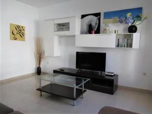 sala de estar con TV y mesa de centro de cristal. en Belvilla by OYO La Maison des Sables, en Corralejo