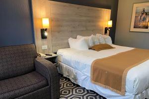 ein Hotelzimmer mit einem Bett und einem Stuhl in der Unterkunft Ramada by Wyndham Medicine Hat in Medicine Hat