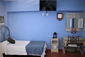 a bedroom with a blue wall with a bed and a desk at Hostal Arco Plaza in Mojácar