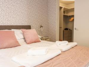 Una cama con sábanas blancas y almohadas rosas. en The Toll House, en Melrose