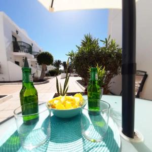 a table with two bottles and a bowl of fruit at Casa Gil Corralejo San Valentin in Corralejo