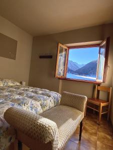a bedroom with a bed and a window and a chair at La Maison De Chouflette in Cogne