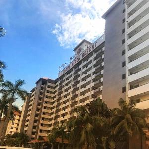 um grande edifício de hotel com palmeiras em frente em Cozy Seaview Glory Beach Resort ANC em Porto Dickson
