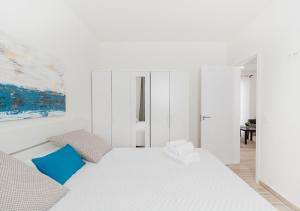 1 dormitorio blanco con 1 cama blanca grande con almohadas azules en Moderno apartamento urbano en barrio histórico 1ºD, en Santa Cruz de Tenerife