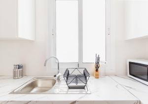 cocina blanca con fregadero y microondas en Moderno apartamento urbano en barrio histórico 1ºD, en Santa Cruz de Tenerife