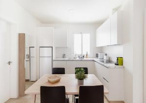 cocina blanca con mesa de madera y sillas en Moderno apartamento urbano en barrio histórico 1ºD, en Santa Cruz de Tenerife