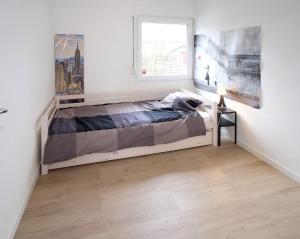 biała sypialnia z łóżkiem i oknem w obiekcie Chalet 2ch au bord de l’Ourthe w mieście Hotton