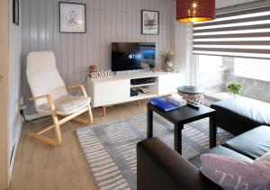 sala de estar con sofá y TV en Chalet 2ch au bord de l’Ourthe en Hotton