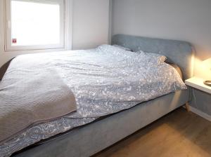 1 cama con edredón blanco y ventana en Chalet 2ch au bord de l’Ourthe en Hotton