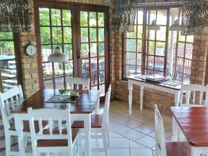 a dining room with white chairs and tables and windows at Xanadu Guest House in Sea Park