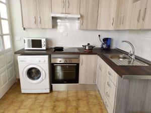 a kitchen with a washing machine and a microwave at Apartamento Carrillo 1 La Rosa in Santa Cruz de Tenerife