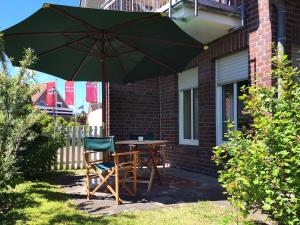 stół i krzesła pod parasolem na patio w obiekcie Ferienwohnung de Vries w mieście Langeoog