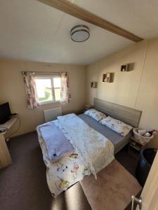 1 dormitorio con 2 camas y ventana en K & K Caravan Southview, en Skegness